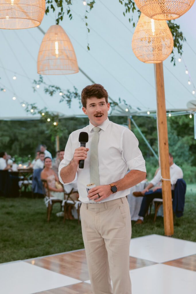 best man standing on a checkered dance floor at a tented wedding