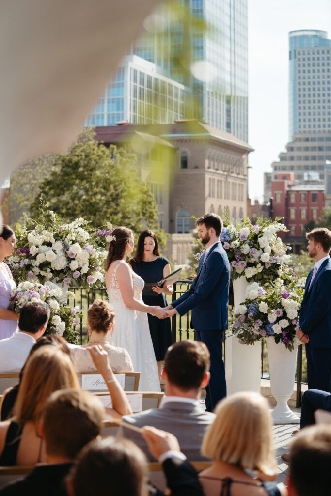 Couple exchanges vows during their intimate wedding ceremony on a rooftop with city views.