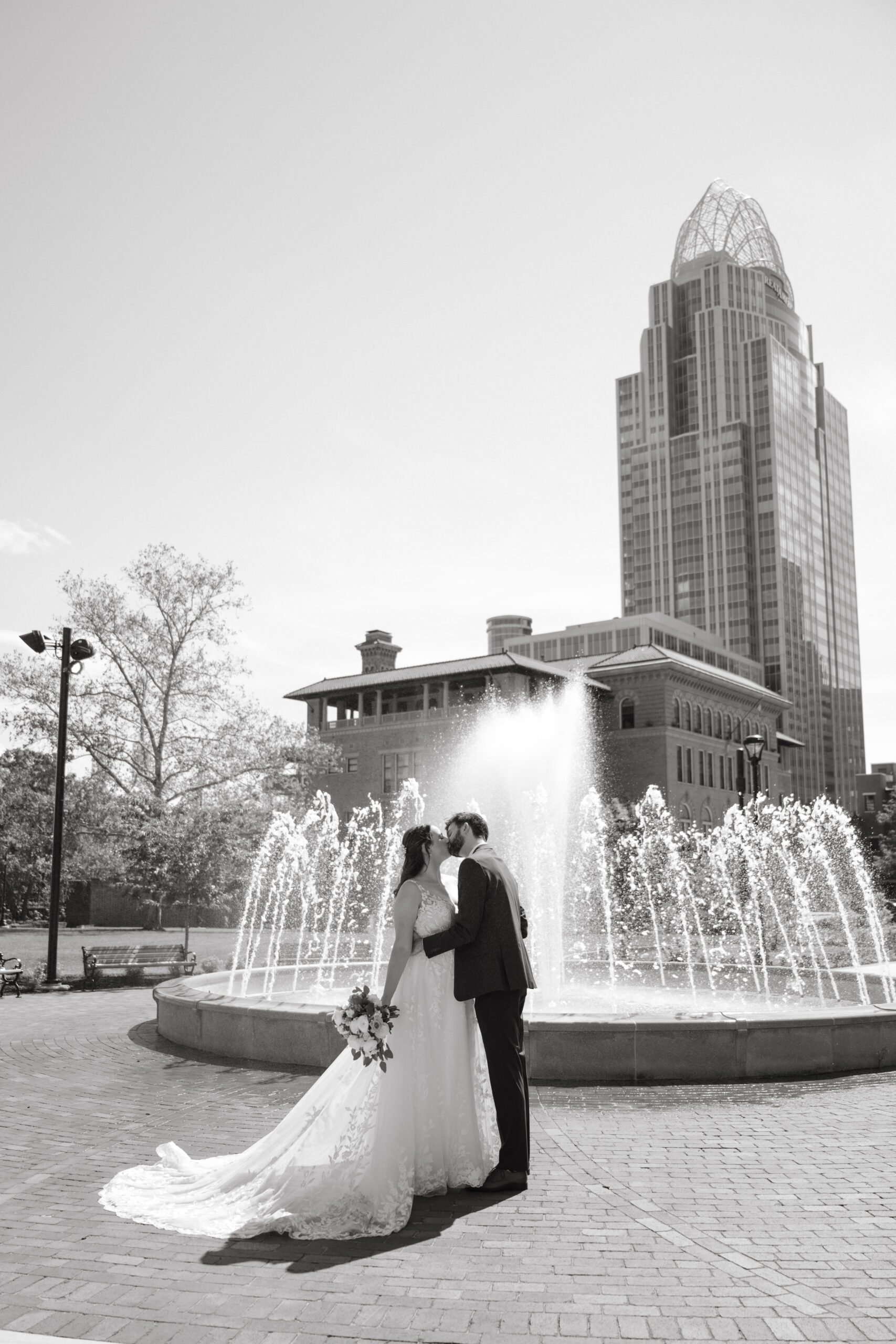 intimate wedding - bride and groom kissing in front of a fountain