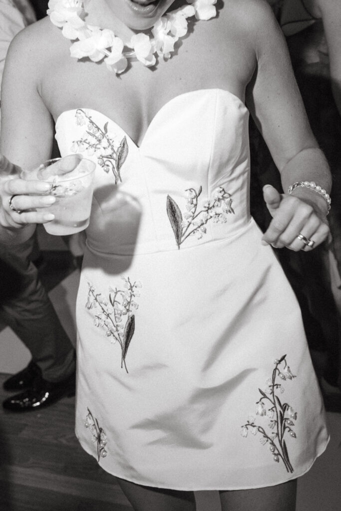 bride in awhite dress with floral accents dress holding a cocktail
