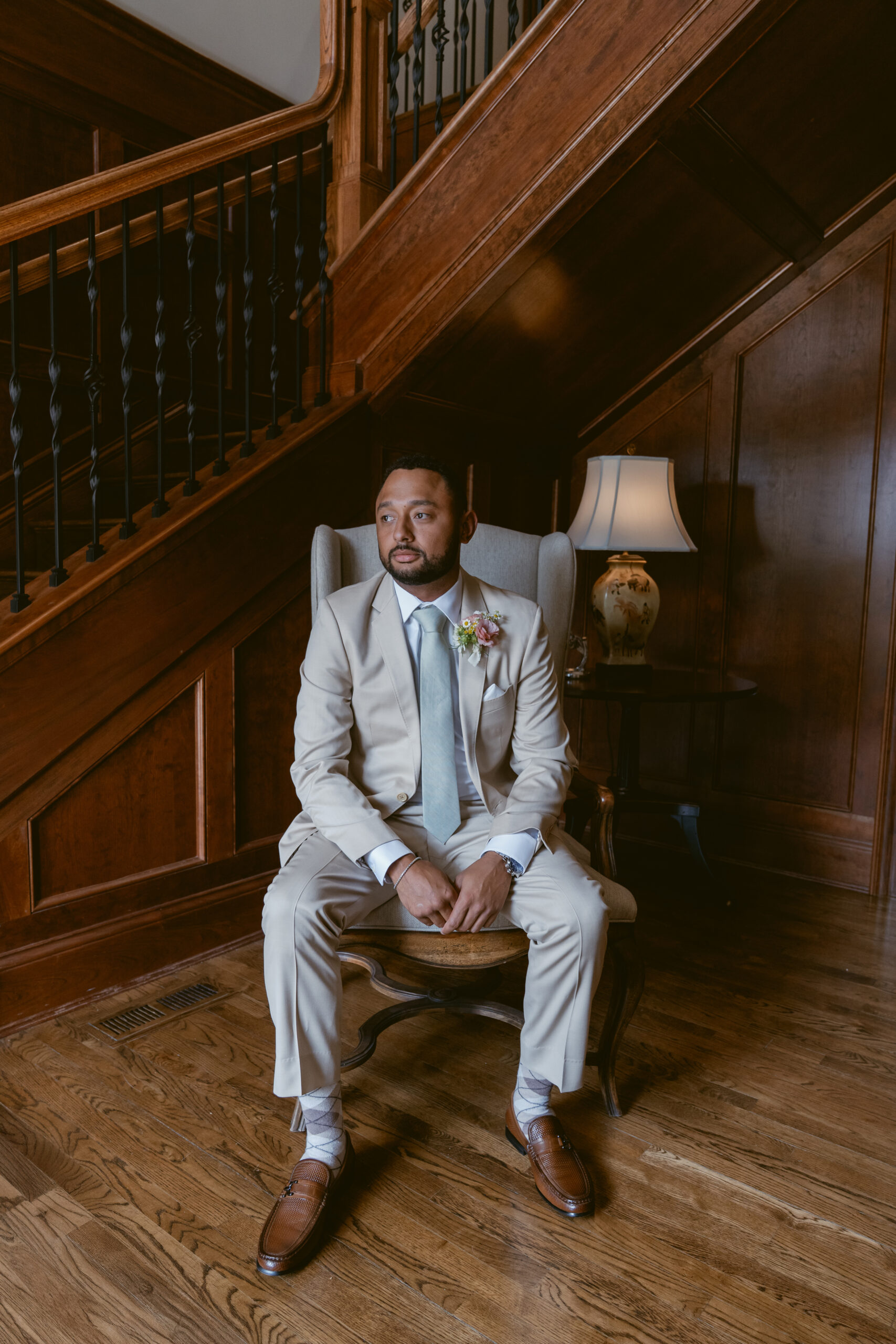 groom sitting down beside the staircase on hisWedding at Meshewa House
