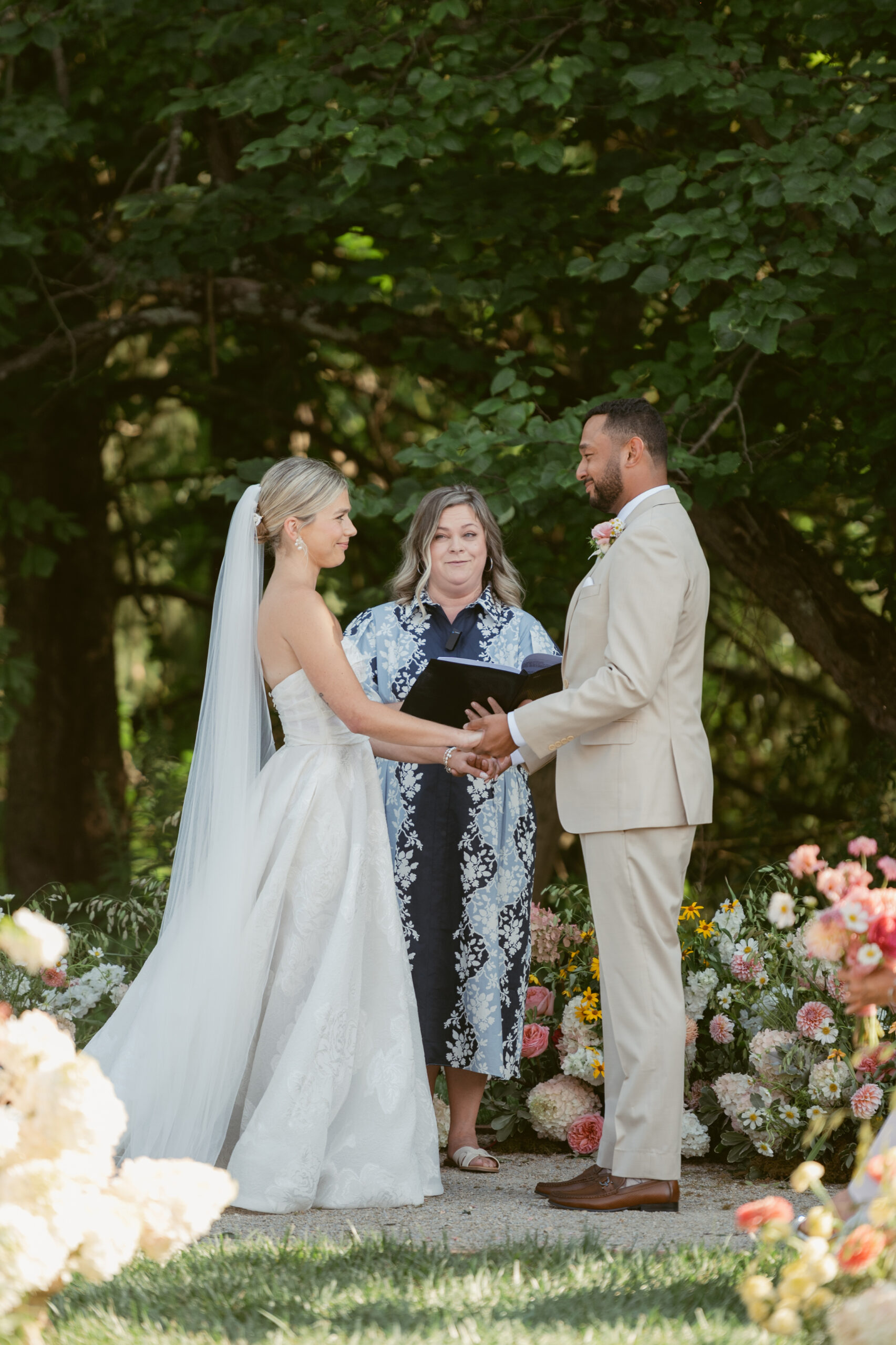 bride and groom standing hand in hand during their wedding ceremony surrounded by lush florals- Wedding at Meshewa House