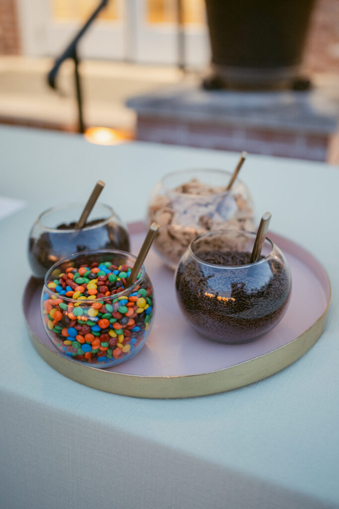 Colorful wedding dessert toppings including mini M&Ms, chocolate sprinkles, and cookie crumbles in glass bowls—Wedding at Meshewa House