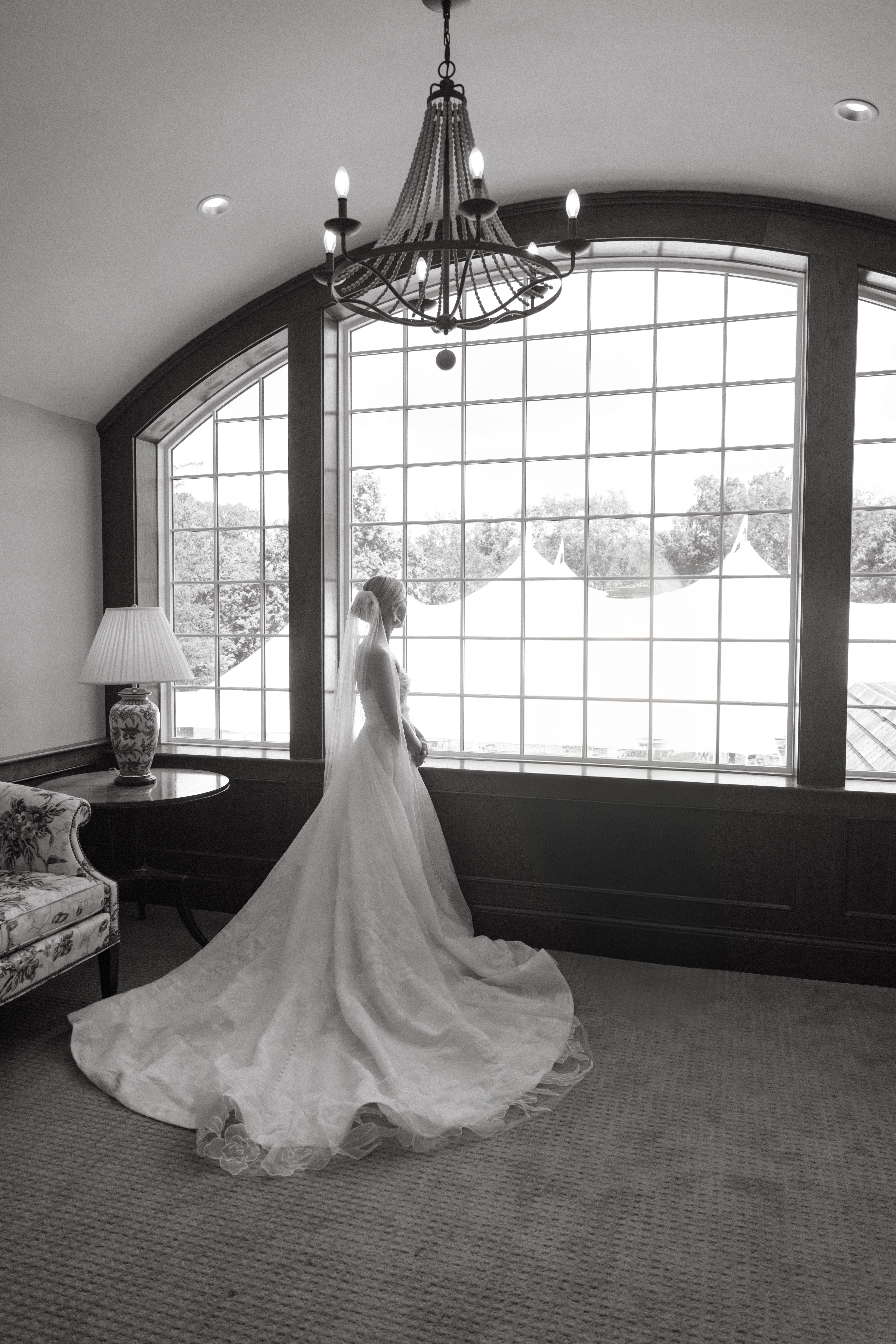 Bride stands in front of large window with cathedral veil and train flowing behind her - Wedding at Meshewa House