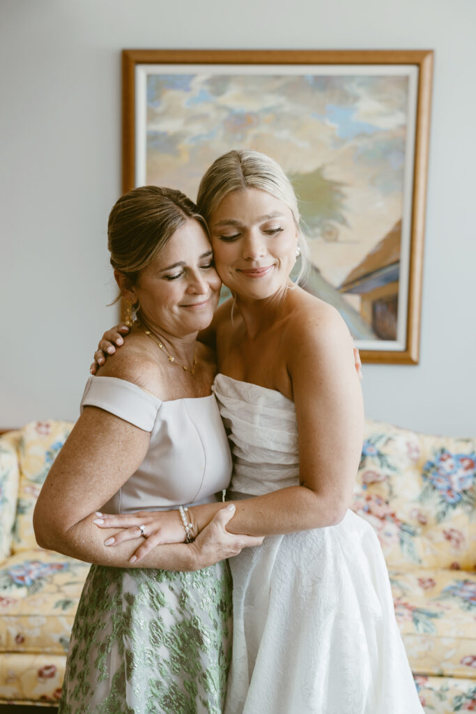 Bride and her mother share a heartfelt embrace before the ceremony in a cozy bridal suite.