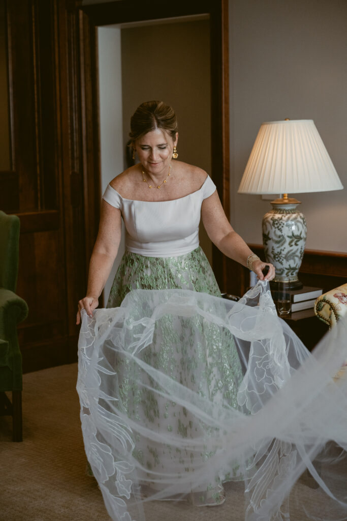 Mother of the bride holding lace veil in soft window light by best wedding photographers in Cincinnati.