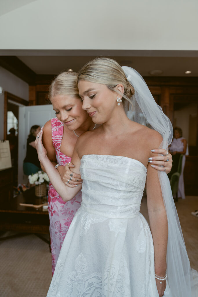 Bride and bridesmaid share a quiet, emotional moment before the ceremony in a bridal suite.