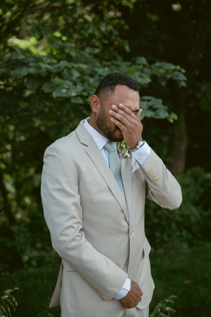 groom watching the bride walk down the isle and getting emotional