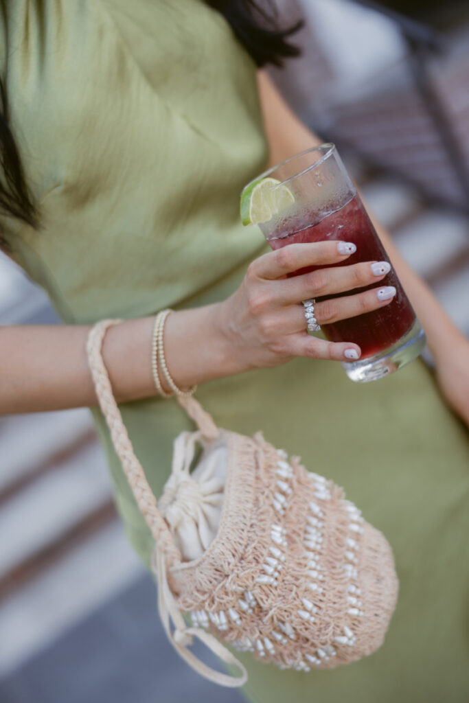 Guest holding a cocktail and woven bag, showcasing thoughtful style choices while designing guest experience.