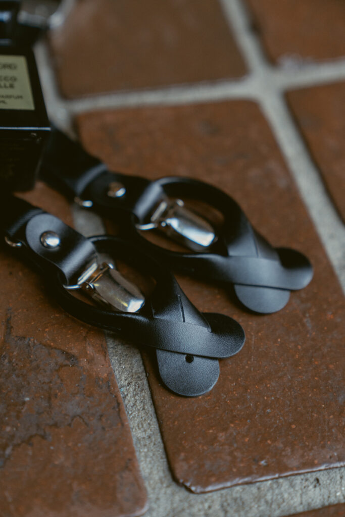 Close-up of black leather suspenders laid out before a Downtown Cincinnati Wedding.