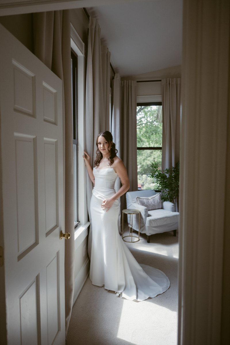 Bride standing by a window in her dress before a Downtown Cincinnati Wedding ceremony.
