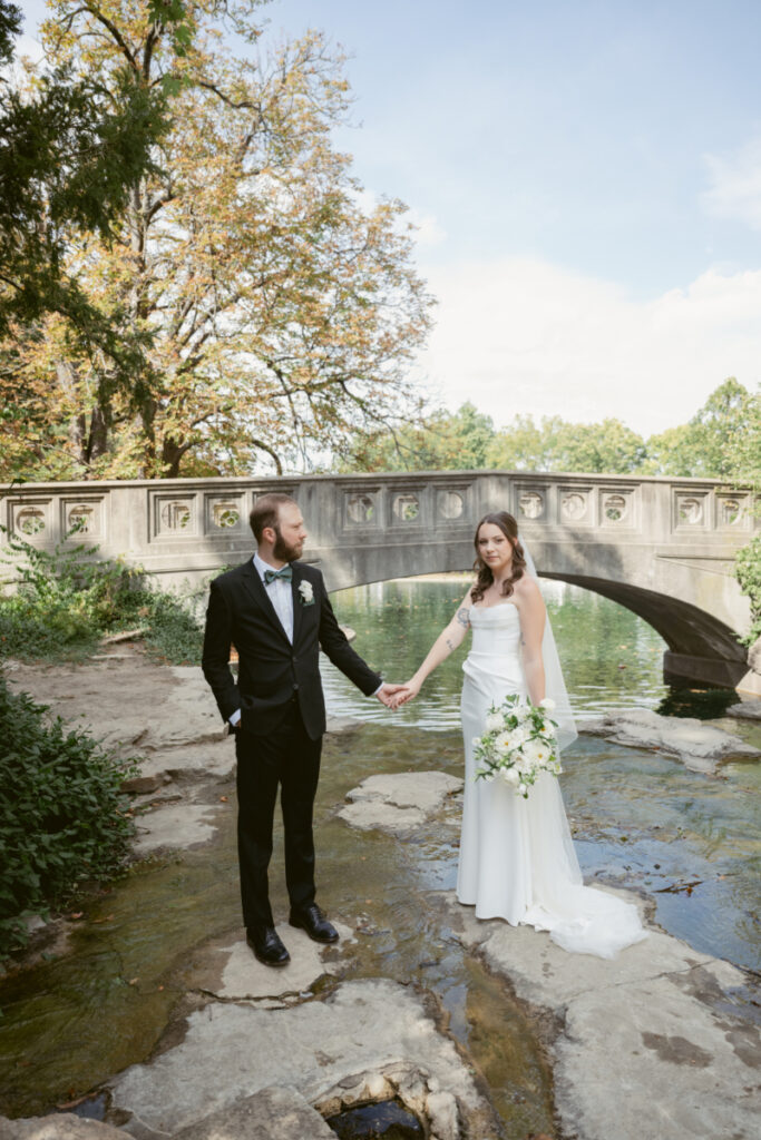 Bride and groom holding hands in front of a stone bridge during their Downtown Cincinnati Wedding.