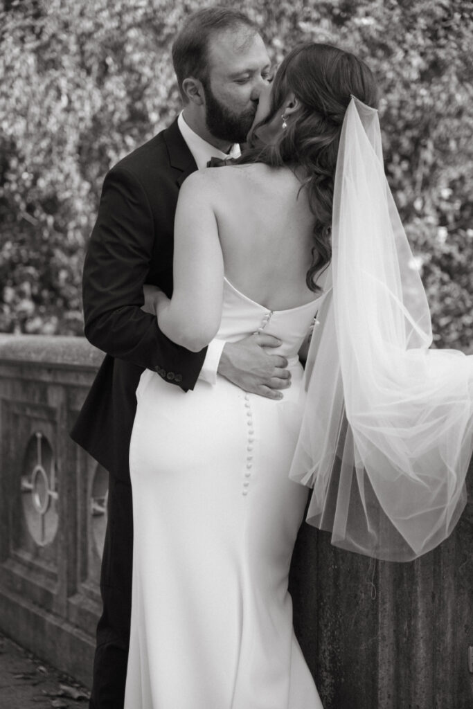Bride and groom share a kiss by a stone railing during their Downtown Cincinnati Wedding portraits.