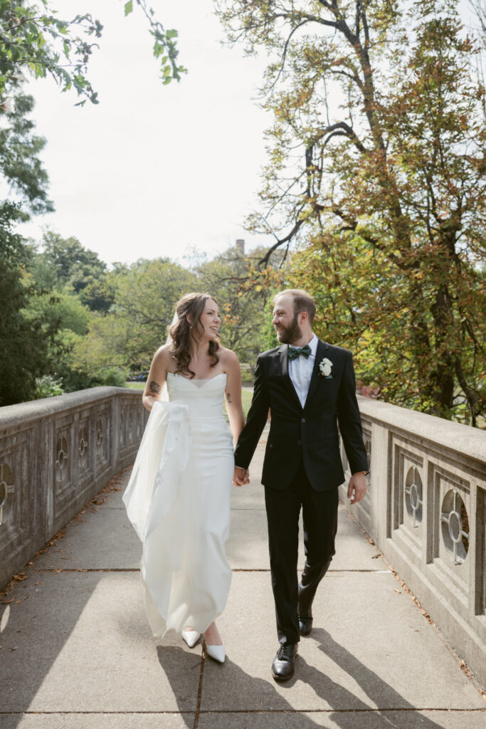 Bride and groom walk hand in hand across a bridge during their Downtown Cincinnati Wedding day.