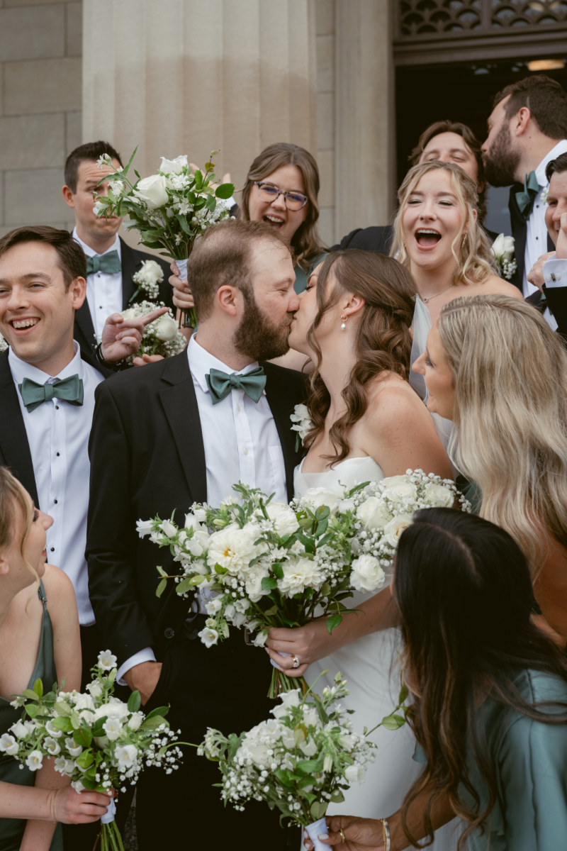 Bride and groom kiss while surrounded by their cheering wedding party during a Downtown Cincinnati Wedding.
