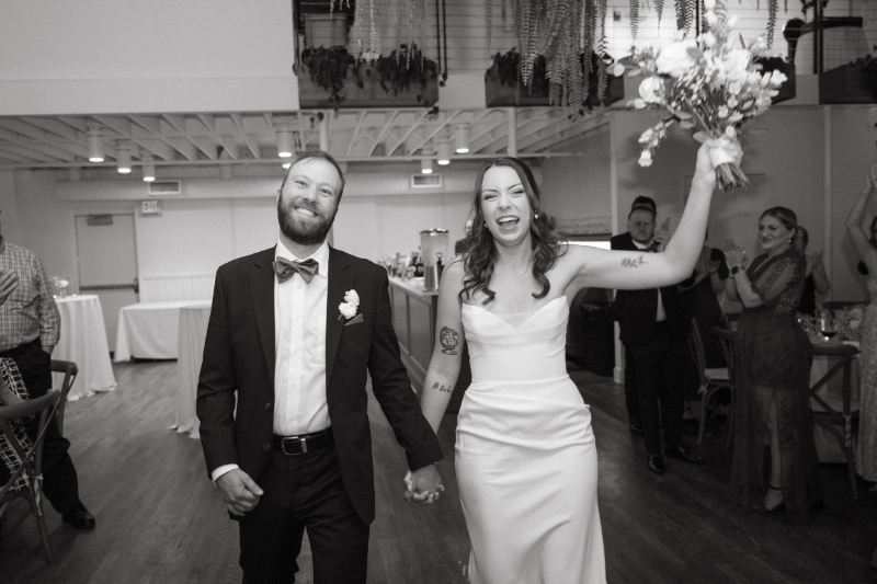 Bride and groom joyfully enter their Downtown Cincinnati Wedding reception, greeted by cheering guests.