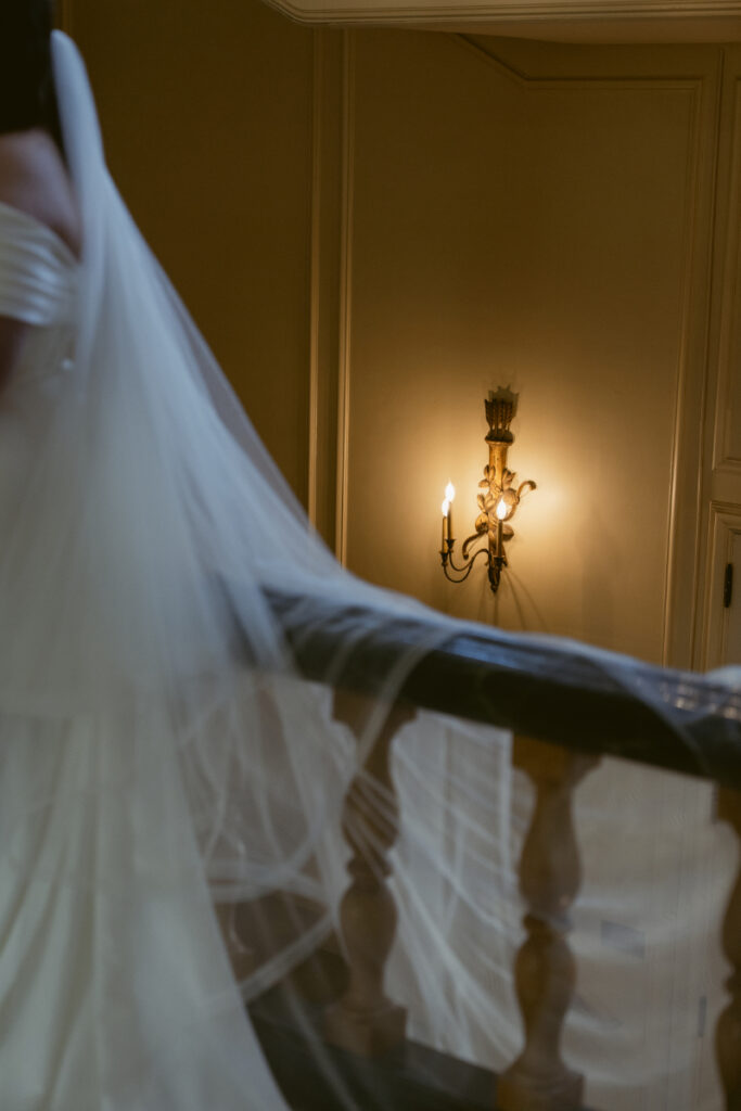 Close-up of bride’s veil flowing over railing inside Kingwood Hall during Ohio garden wedding.