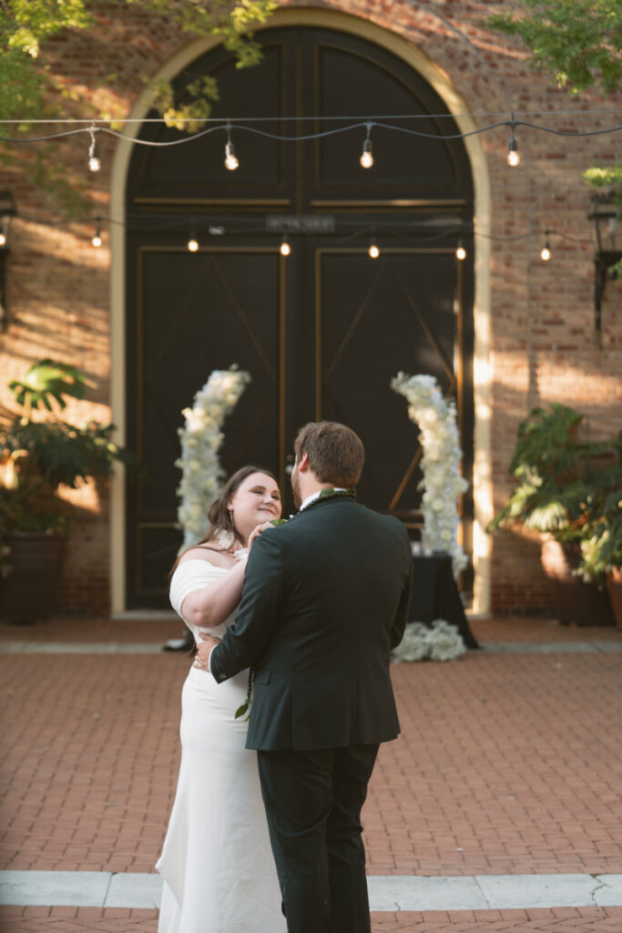 Bride and groom share a joyful first dance in the courtyard during their Ohio garden wedding.