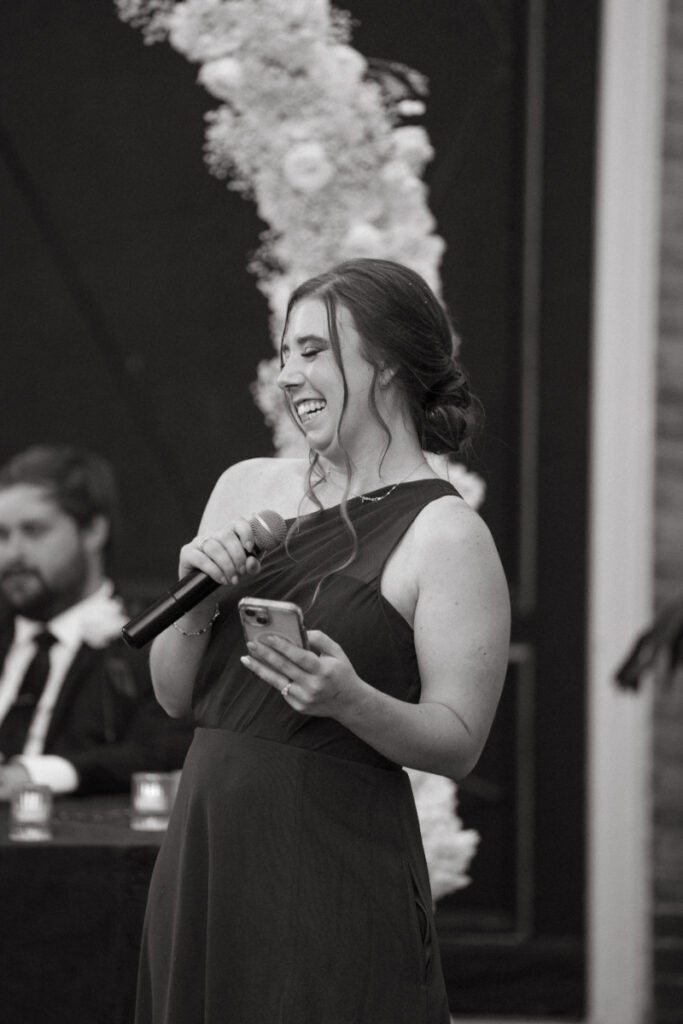 Bridesmaid laughing while giving a toast during an Ohio garden wedding reception under floral décor.