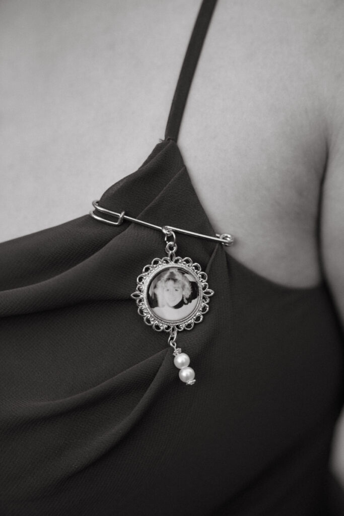 Close-up of a memorial pin worn on a dress during an emotional Ohio garden wedding celebration.