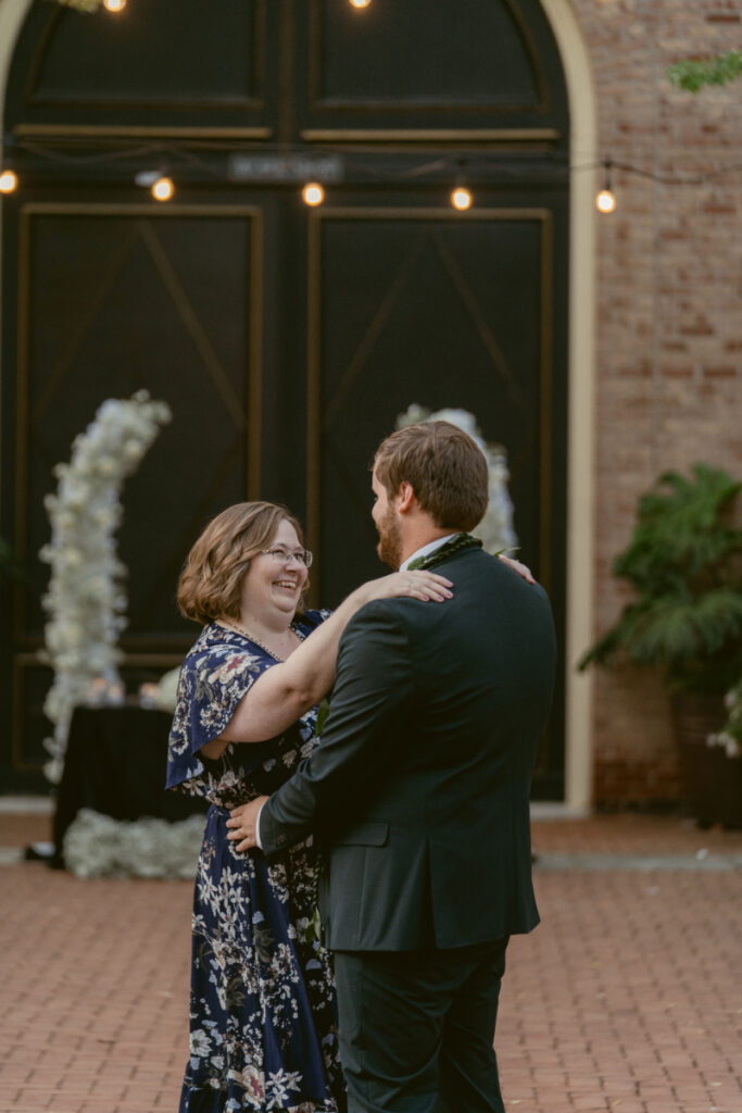 Groom shares a joyful dance with his mother in the courtyard during the wedding reception.