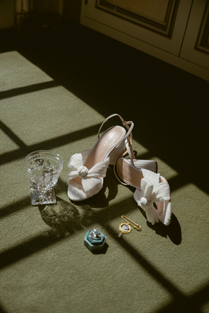 Bridal shoes, jewelry, and perfume styled in sunlight