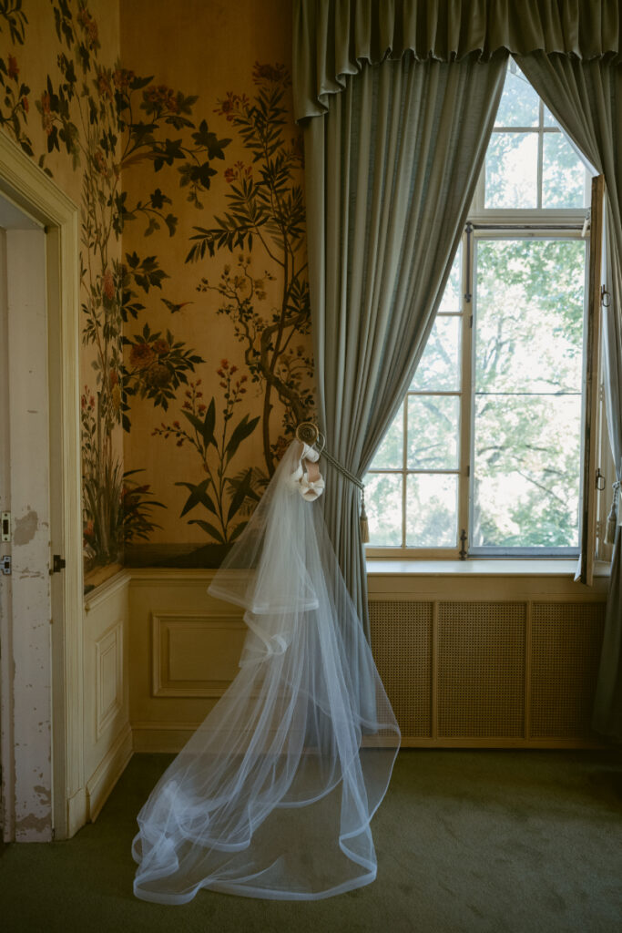 Bridal veil and heels hang in sunlit window of historic mansion