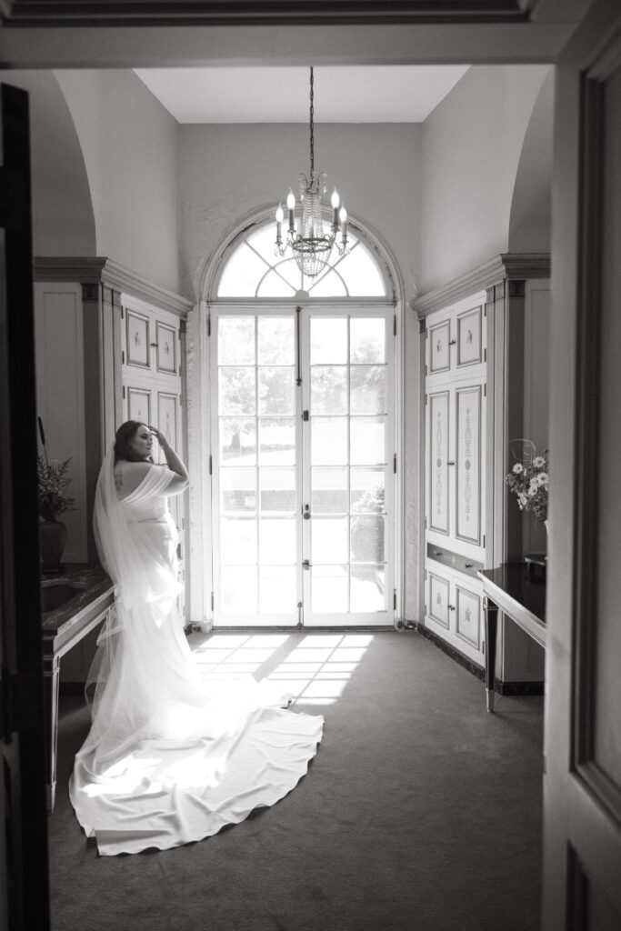 Bride stands in front of arched window inside historic mansion