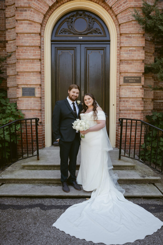 Bride and groom smile on the steps of Kingwood Hall during their Ohio garden wedding celebration.