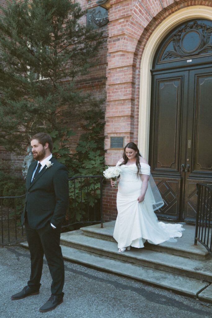 Bride walking toward groom for first look outside historic mansion at their Ohio garden wedding.