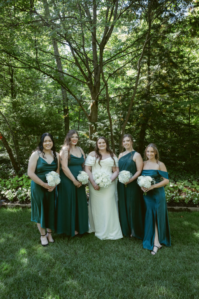 Bride smiling with white bouquets surrounding her during sunny outdoor portrait at Ohio garden wedding.