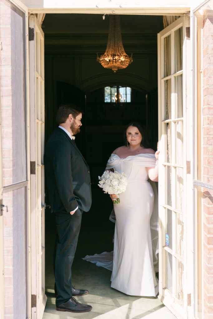 Bride and groom share first look in doorway of historic building during Ohio garden wedding.