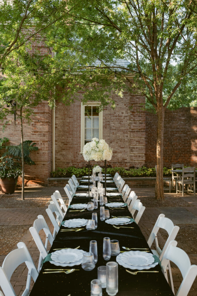 Long outdoor reception table with black linens and white centerpieces at an Ohio garden wedding.