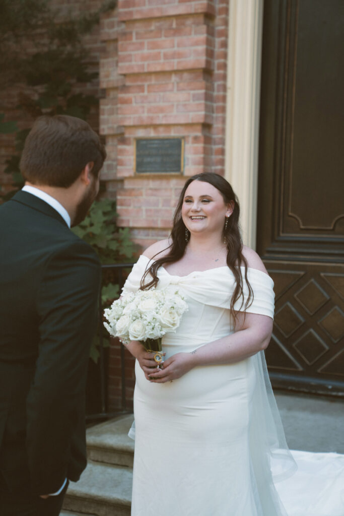 Bride smiling at groom during their first look outside Kingwood Hall at an Ohio garden wedding.