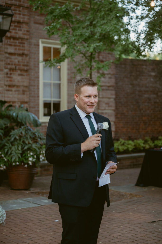 Groomsman gives a heartfelt speech during the Ohio garden wedding reception in the courtyard.