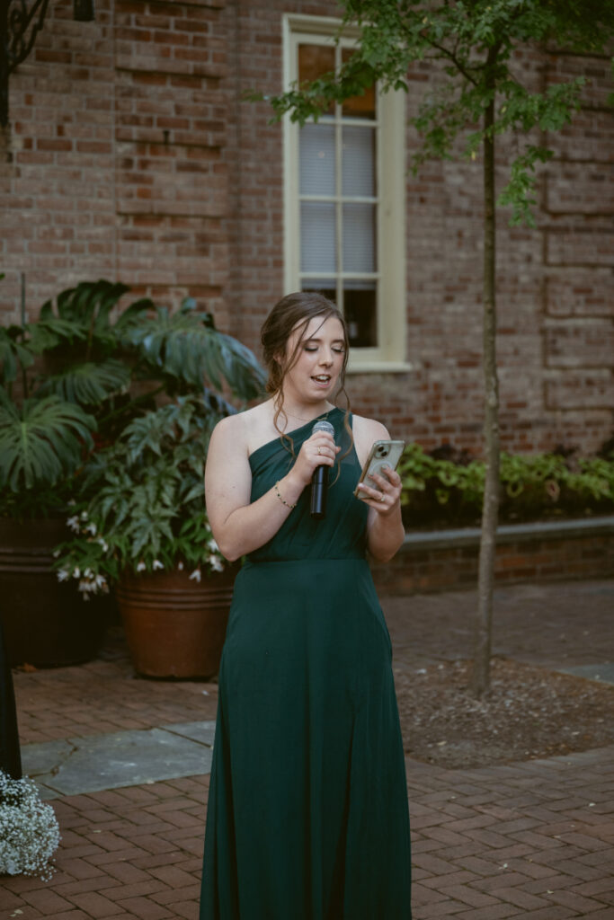Bridesmaid reads a toast from her phone during an outdoor Ohio garden wedding reception.