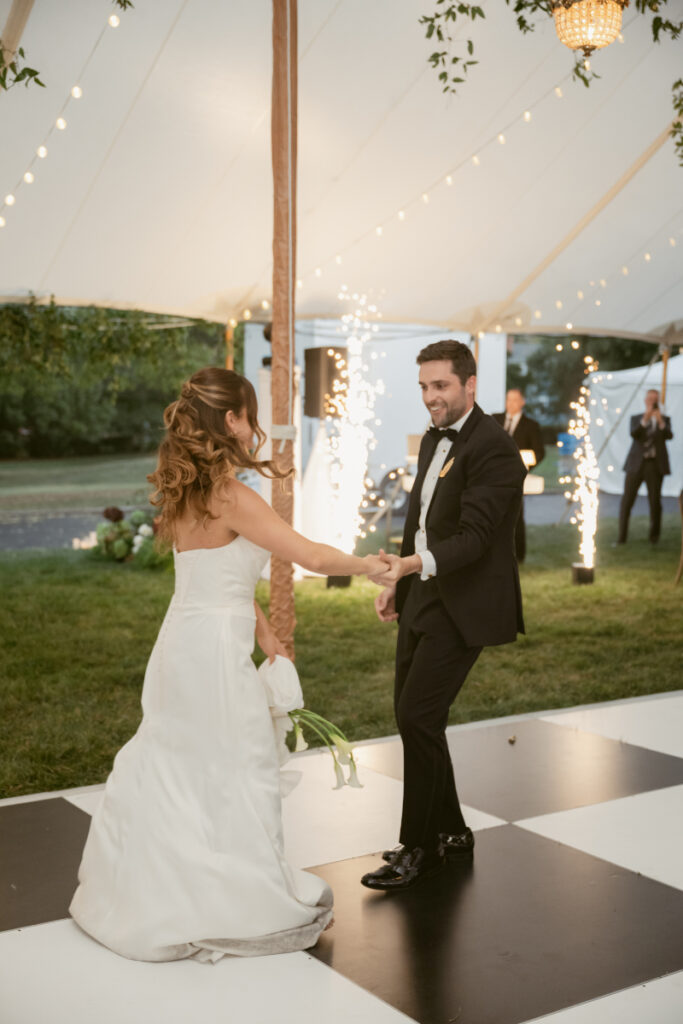 bride and groom sharing their first dance with fireworks going off in the background