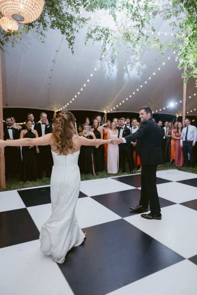 bride and groom dancing at their wedding reception while guests watch in the background