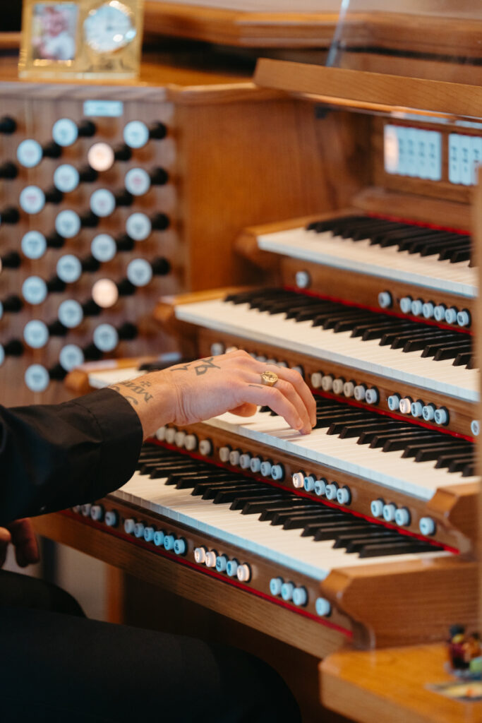 Musician playing a church organ during the Catholic ceremony at a Laurel Court wedding.