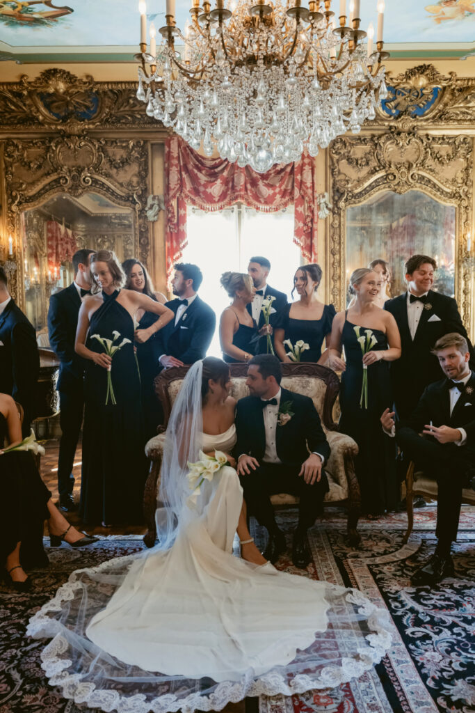 bride and groom sitting down with their bridal party standing around them