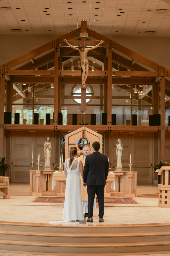 Bride and groom standing at the altar during Catholic vows before their Laurel Court wedding celebration.