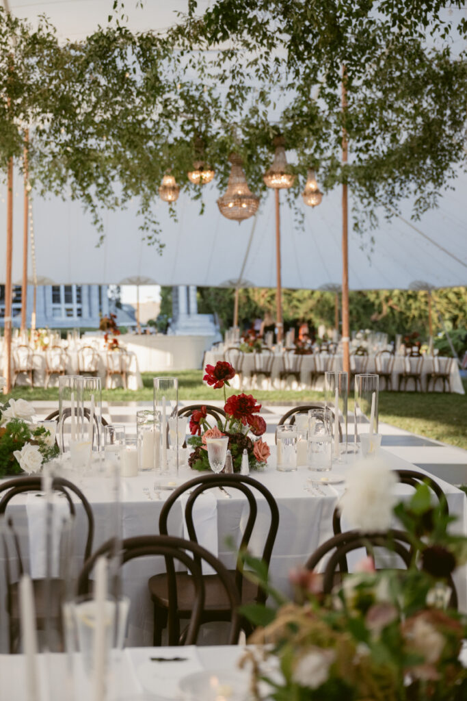 Tented wedding reception with a checkerboard dance floor and hanging green florals