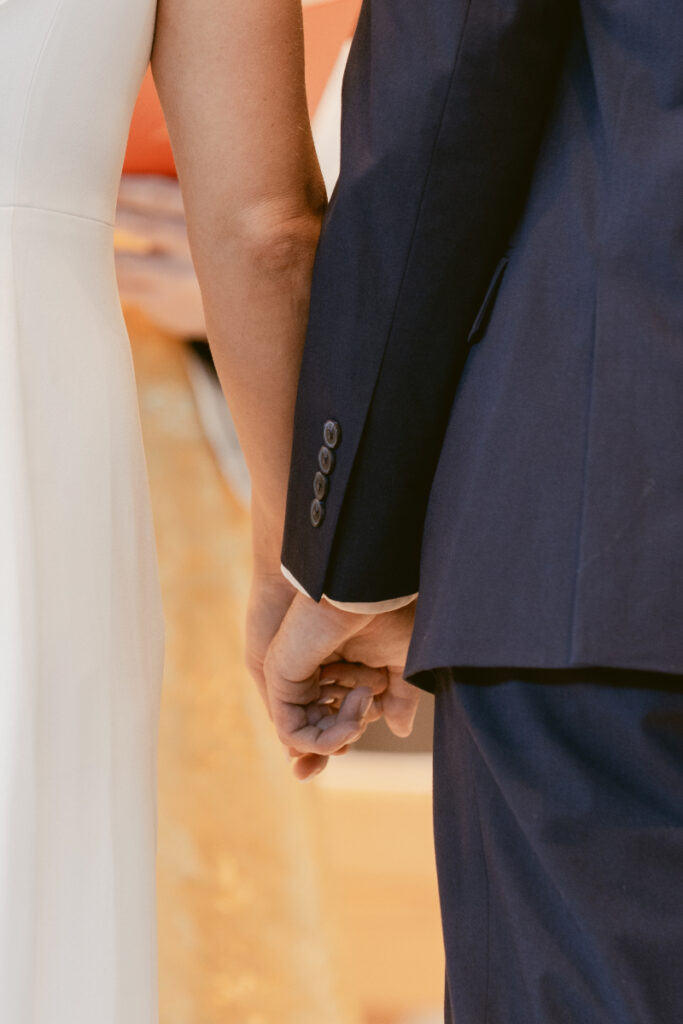 Close-up of couple holding hands during their Catholic ceremony before the Laurel Court wedding.