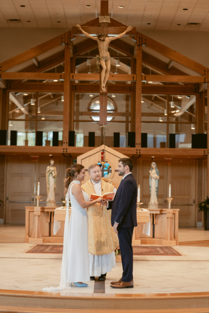 Bride and groom exchange vows during Catholic ceremony ahead of their Laurel Court wedding celebration.