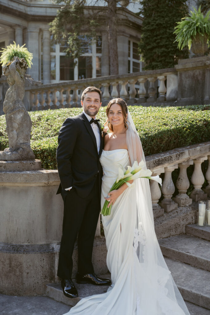 Bride and groom share a kiss in the garden with mansion backdrop during their Laurel Court wedding.