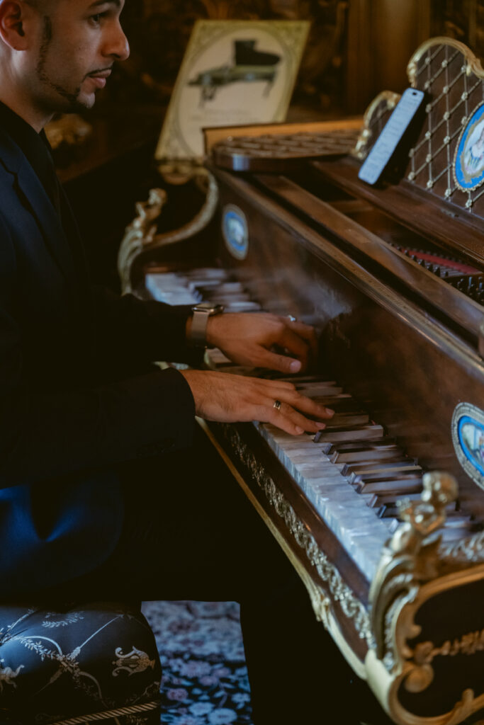Close-up of musician playing an ornate vintage piano with phone sheet music in elegant room.