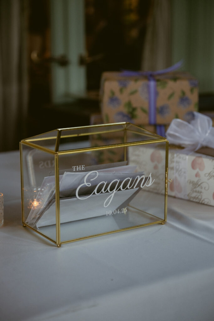 Glass card box with gold frame and “The Eagans” written on the front, surrounded by gifts.