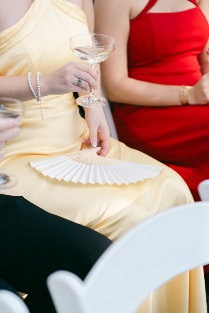Guests seated with champagne and paper fans during outdoor Laurel Court wedding in Cincinnati.