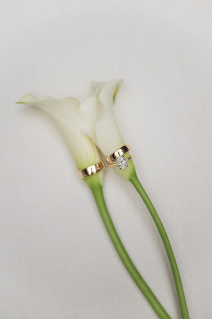 Wedding rings on calla lilies styled for detail photos before a Laurel Court wedding celebration.