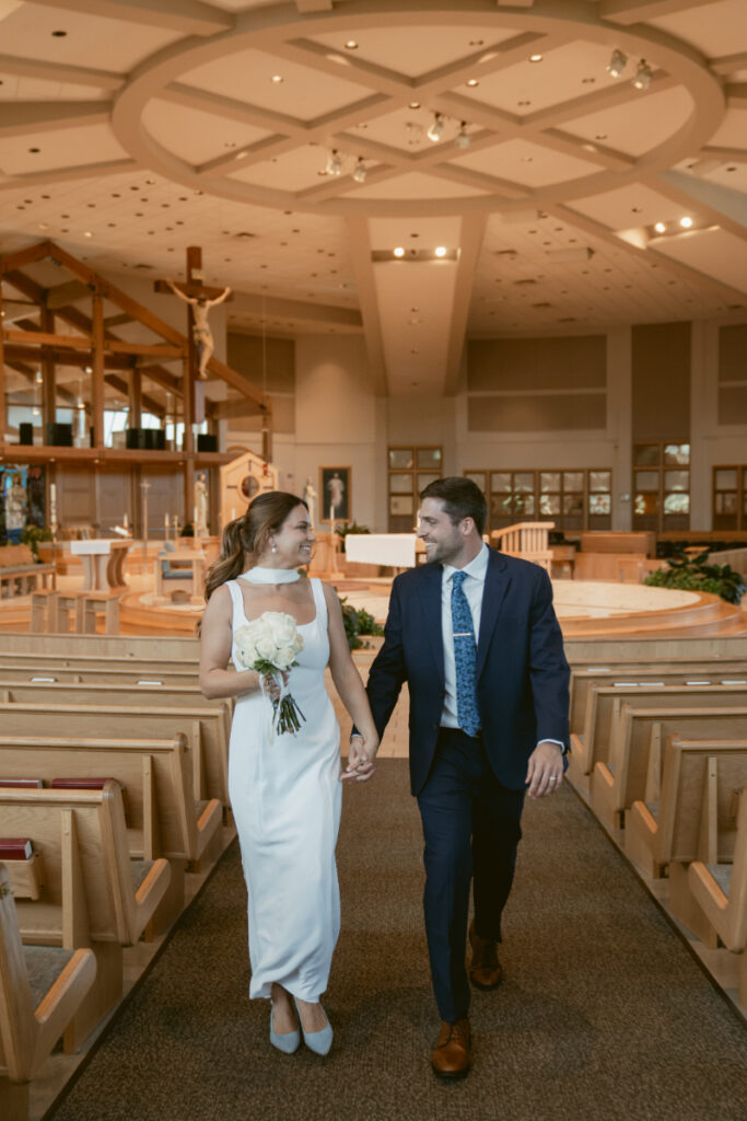 Bride and groom walk down the aisle after their Catholic ceremony before their Laurel Court wedding.